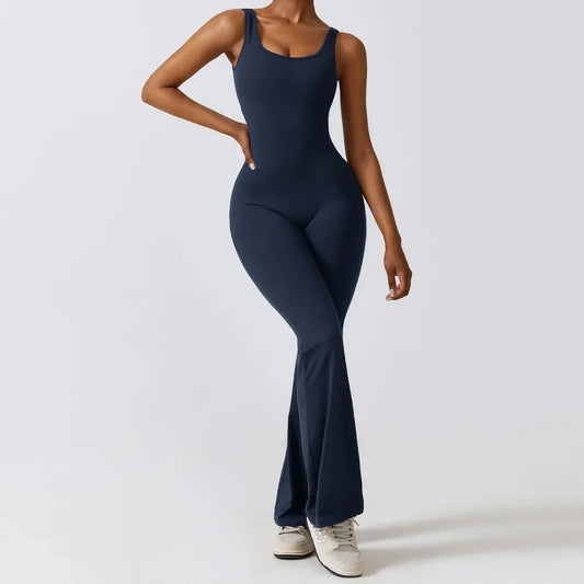 Woman wearing navy FlareFlex Jumpsuit with flared legs and sleeveless design, standing against a plain background